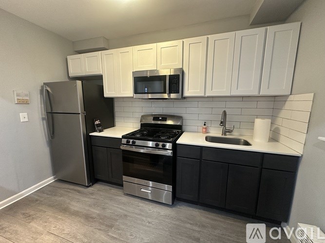 A kitchen with black cabinets and a stainless steel refrigerator.