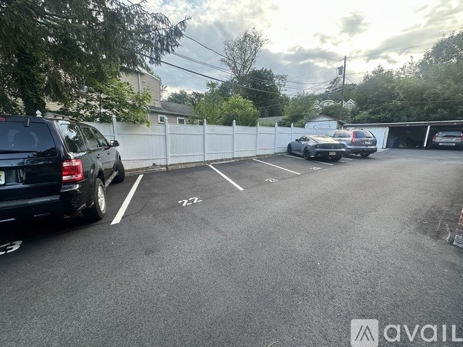 A parking lot with cars and a white fence.