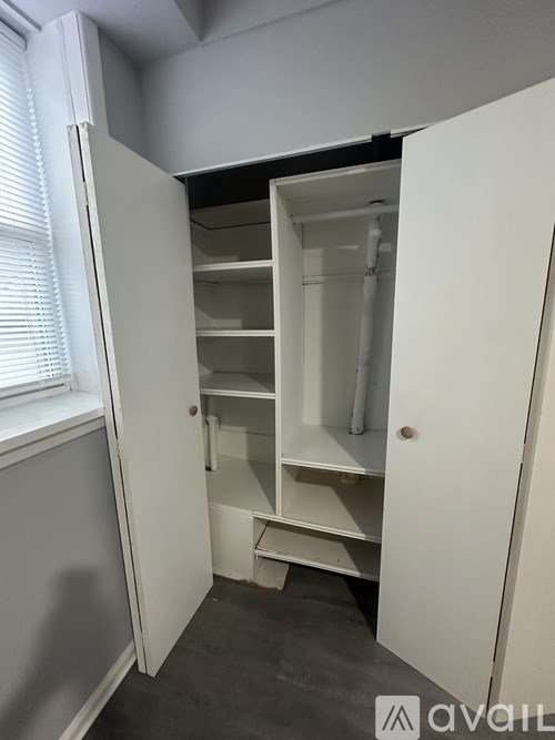 A white closet with shelves and a window.