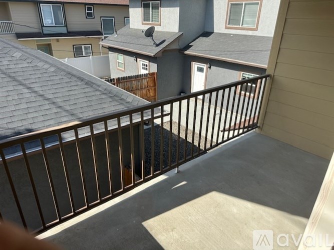 A balcony with a black railing and a view of other apartment buildings.