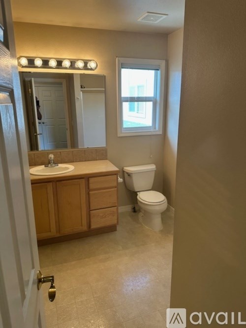 A bathroom with a toilet, sink, and mirror.