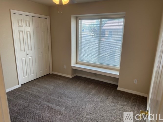 A room with a carpeted floor, a window with blinds, and a door.
