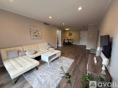 A living room with a white sofa and a grey rug.