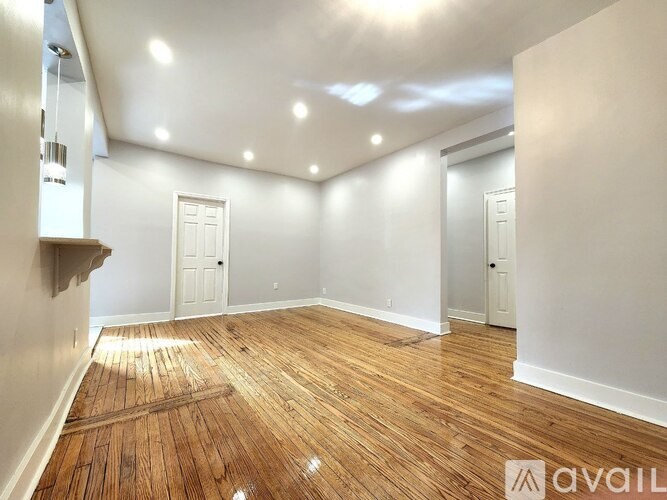 A room with wooden flooring and white walls.