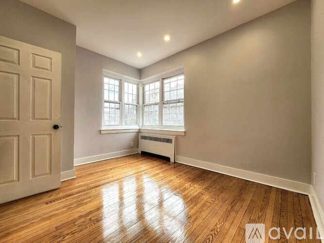 A room with wooden floors and a window with a radiator beneath it.