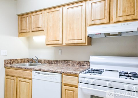 A kitchen with a white stove and wooden cabinets.