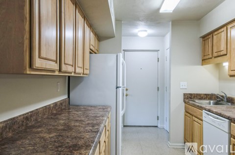 A kitchen with brown cabinets and a white refrigerator.
