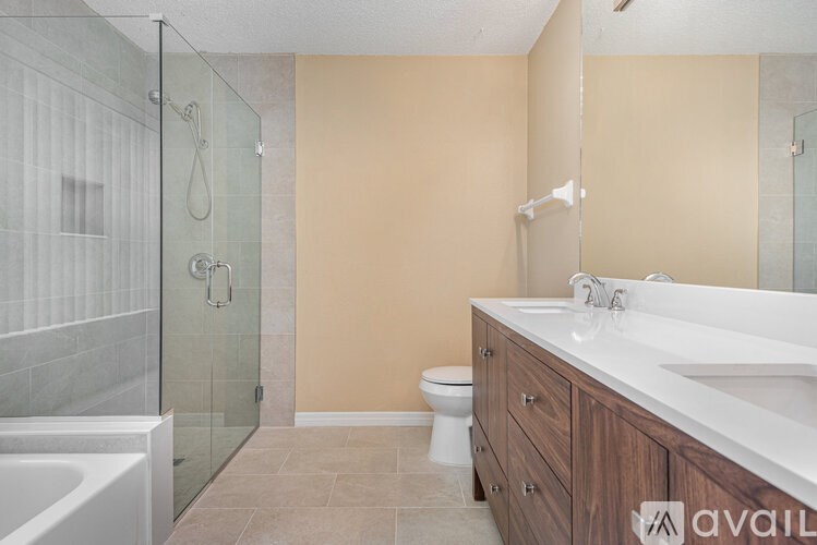 A bathroom with a glass shower stall, a toilet, a bathtub, and a sink.