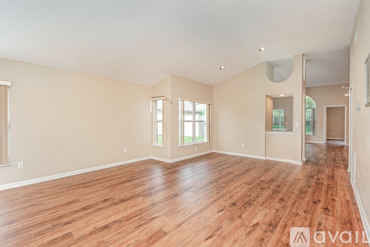A spacious room with wooden flooring and a large window.