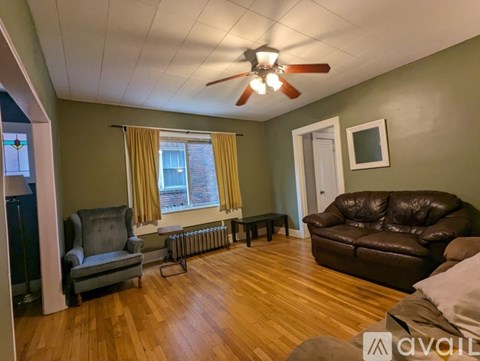 A living room with a brown leather couch and a grey armchair.