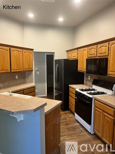 A kitchen with wooden cabinets and a black refrigerator.