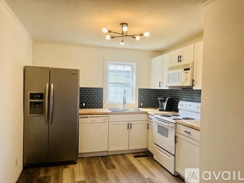 A kitchen with a stainless steel refrigerator and white cabinets.