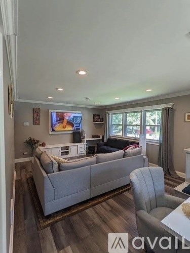 A living room with a grey couch and a television on the wall.