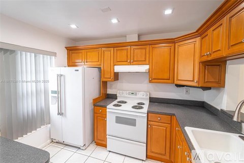 A kitchen with white appliances and wooden cabinets.