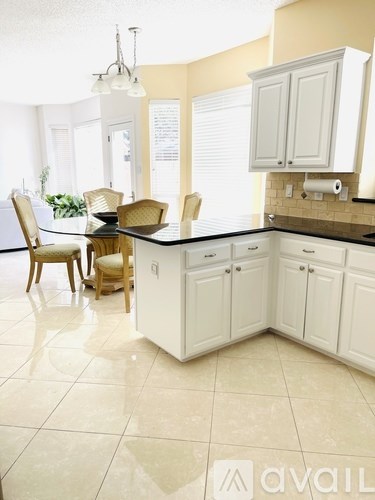 A kitchen with white cabinets and a black countertop.