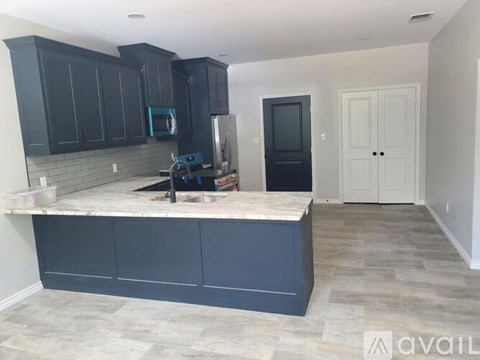 A kitchen with dark cabinets and a marble countertop.