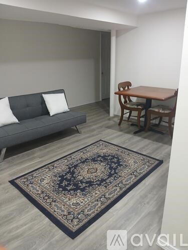 A living room with a grey couch, a wooden table, and a rug.