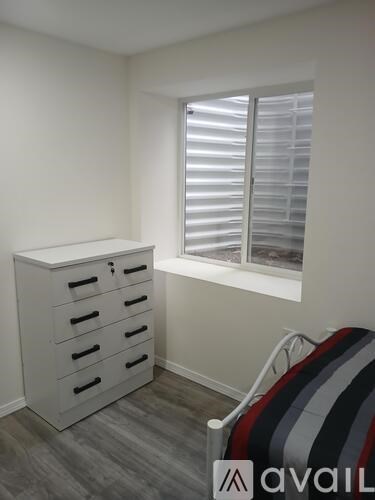 A room with a white cabinet and a striped chair.