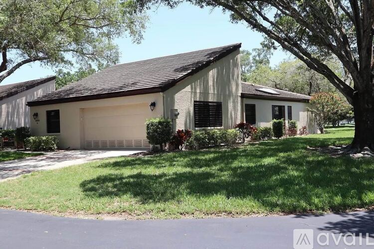 A house with a garage and a tree in front.