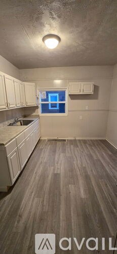 A kitchen with white cabinets and a window.