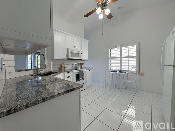 A kitchen with white cabinets and a marble countertop.