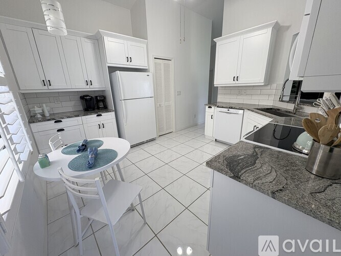 A kitchen with white cabinets and a marble countertop.
