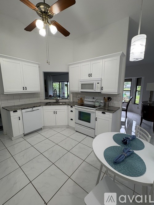 A kitchen with white cabinets and a ceiling fan.