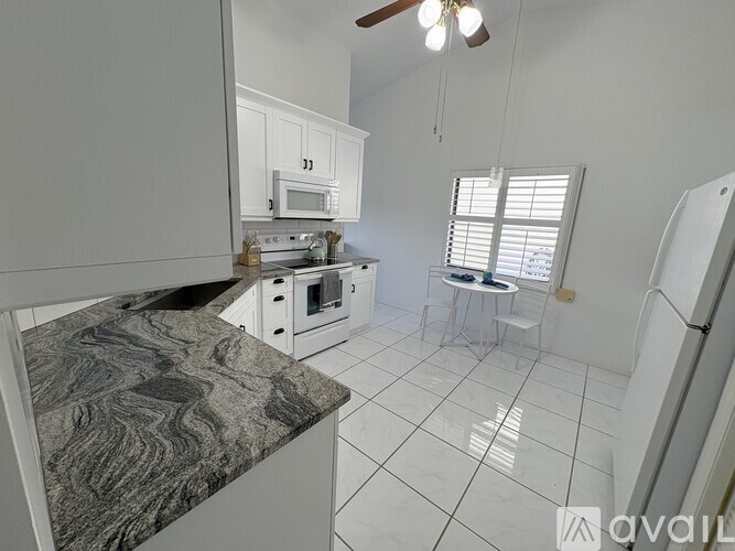 A kitchen with a marble countertop and white cabinets.
