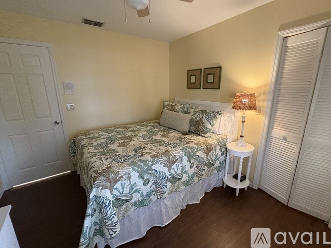 A bedroom with a bed, a nightstand, and a lamp.