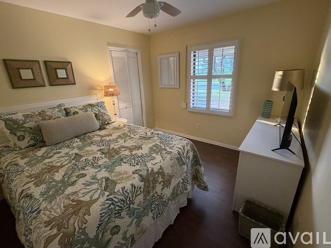 A bedroom with a bed, a dresser, and a ceiling fan.