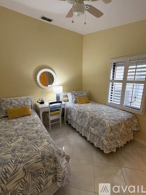 Two twin beds in a room with a ceiling fan.