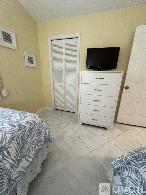 A bedroom with a bed, dresser, and TV.