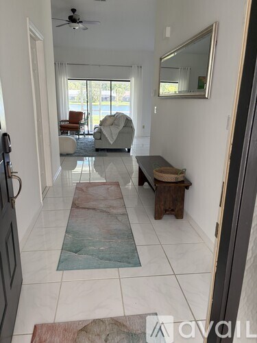 A hallway with a rug on the floor and a bench on the side.