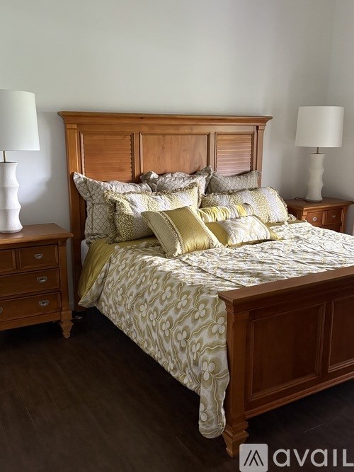 A bed with a wooden headboard and a patterned comforter with matching pillows and lamps on the side.