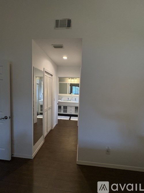 A hallway with a white door and a mirror on the wall.