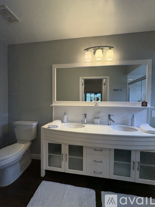 A bathroom with a toilet, sink, and mirror.