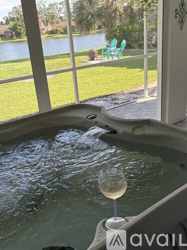 A hot tub with a glass of wine in front of it.