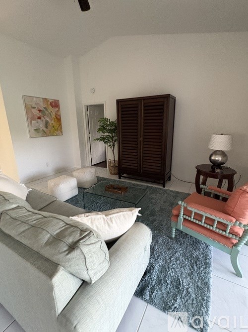 A living room with a white couch and a pink chair.