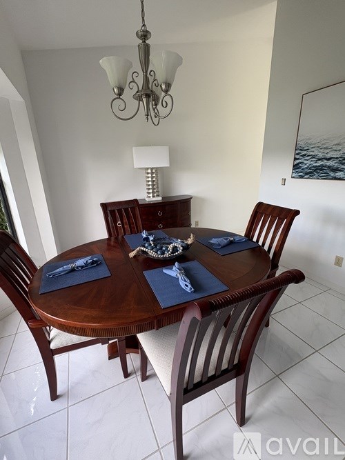 A wooden dining table with chairs and a chandelier in a room.
