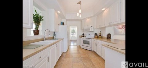 A kitchen with white cabinets and a tiled floor.