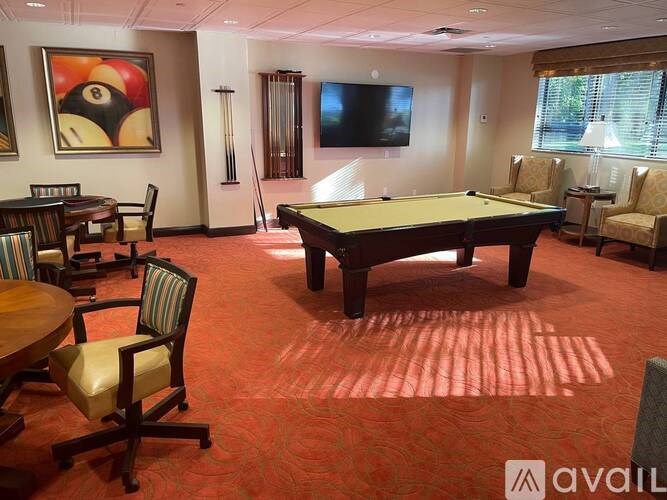 A room with a pool table, chairs, and a television.