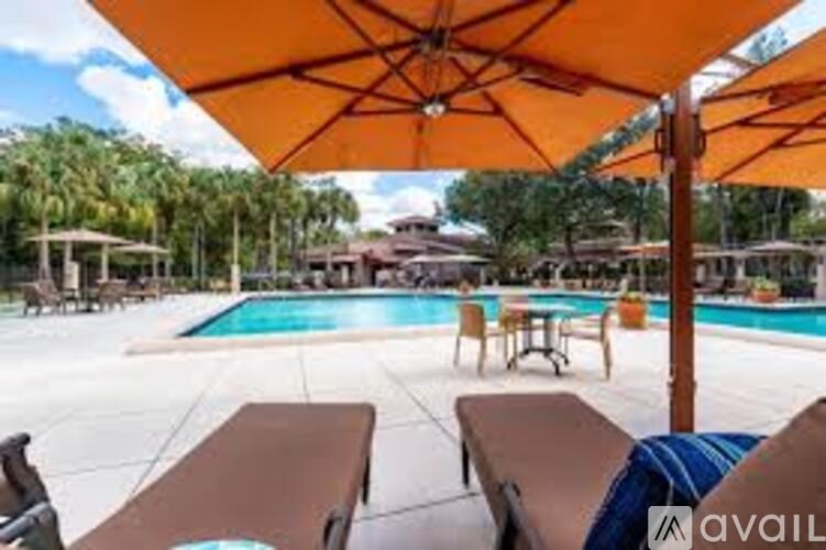 A pool area with sun loungers and an orange umbrella.
