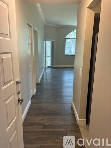 A long hallway with white doors and a wooden floor.