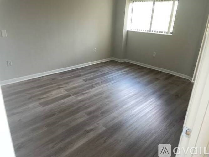 A room with wooden flooring and a window with blinds.
