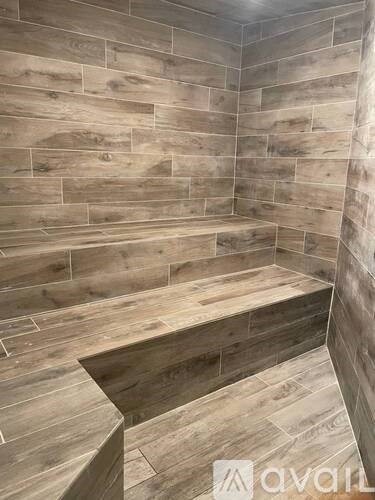 A bathroom with a wooden floor and wall tiles.