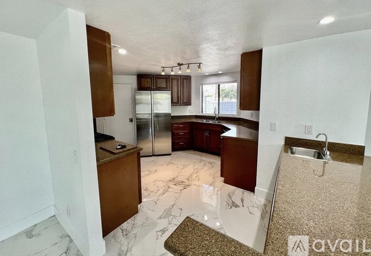 A kitchen with a marble floor and a refrigerator.