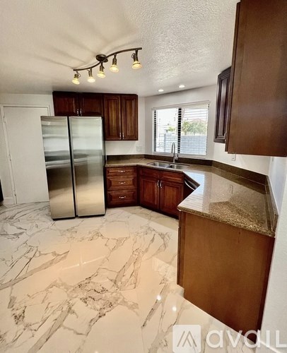 A kitchen with a marble floor and wooden cabinets.