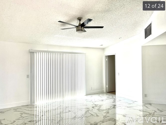 A room with a ceiling fan and marble flooring.