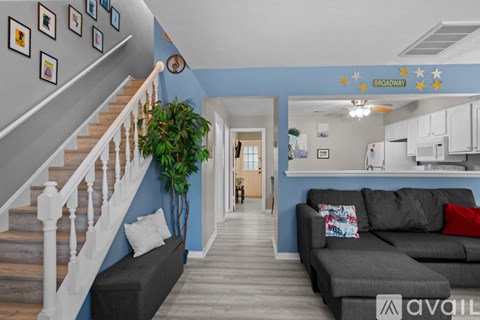 A living room with a grey couch and a staircase with a wooden banister.