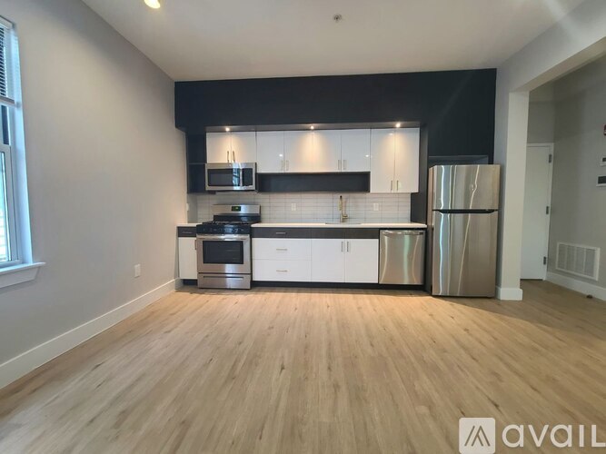 A kitchen with stainless steel appliances and wooden flooring.